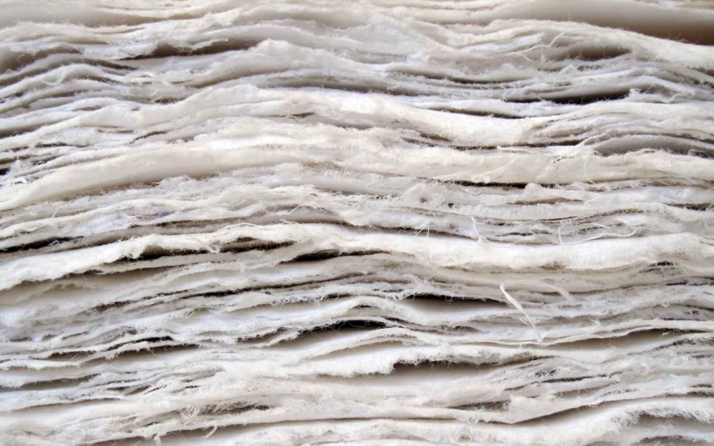 a textural image show a stack of new paper with raw edges