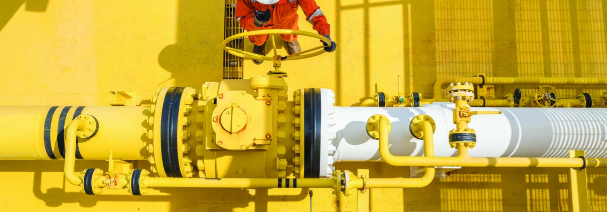 man turning a large valve on a large pipe structure