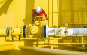 man turning a large valve on a large pipe structure